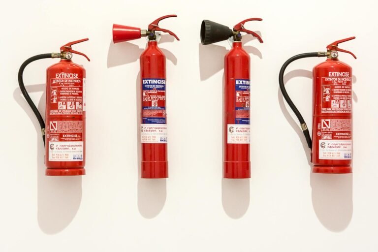 Quatre extincteurs portatifs alignés sur un mur blanc
